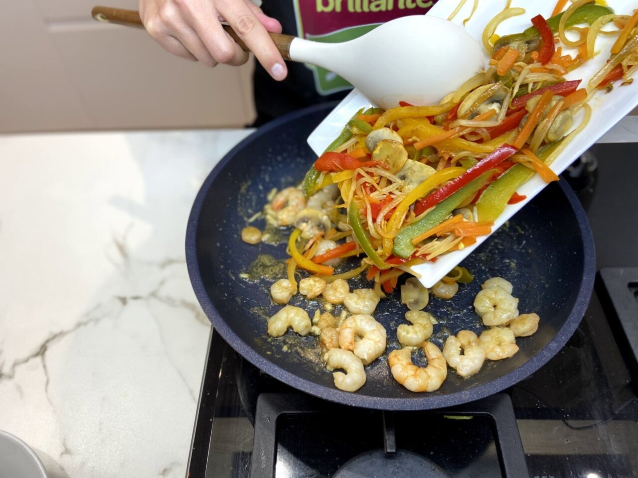 añadir las verduras salteadas a las gambas