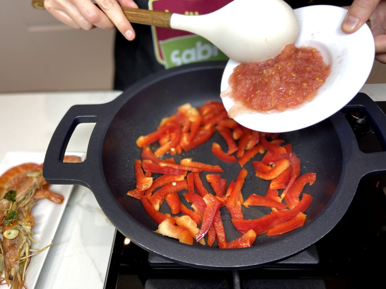 vertemos la mezcla de pimiento y tomate en la paellera caliente