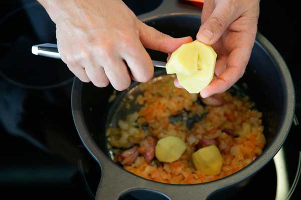 Pelamos y cortamos las patatas y las incorporamos a la olla junto al pimentón
