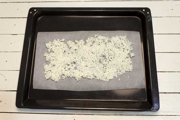 Extender el arroz cocido en una bandeja del horno sobre papel antiadherente