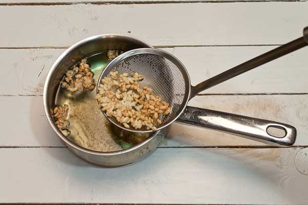 Añadir poco a poco el arroz sobre la olla con aceite y escurrir