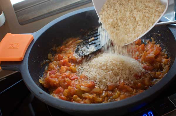 Añadimos el arroz a la mezcla de tomate y cebolla, y salteamos.