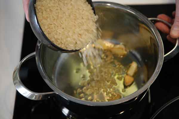 añade el arroz a la olla junto a los ajos y el aceite