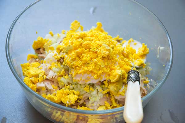 Pelamos los huevos , los abrimos por la mitad y añadimos la mitad de las yemas picadas a la ensalada de arroz.