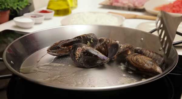 Abrimos los mejillones sobre la paella