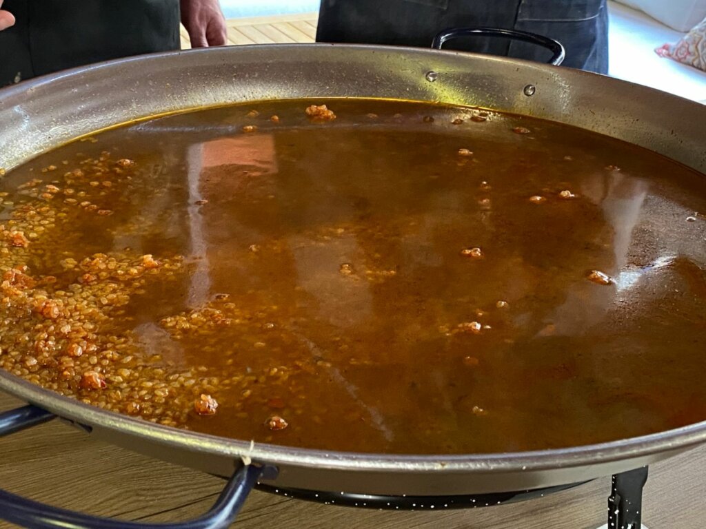 Colamos el caldo y lo vertimos en la paella