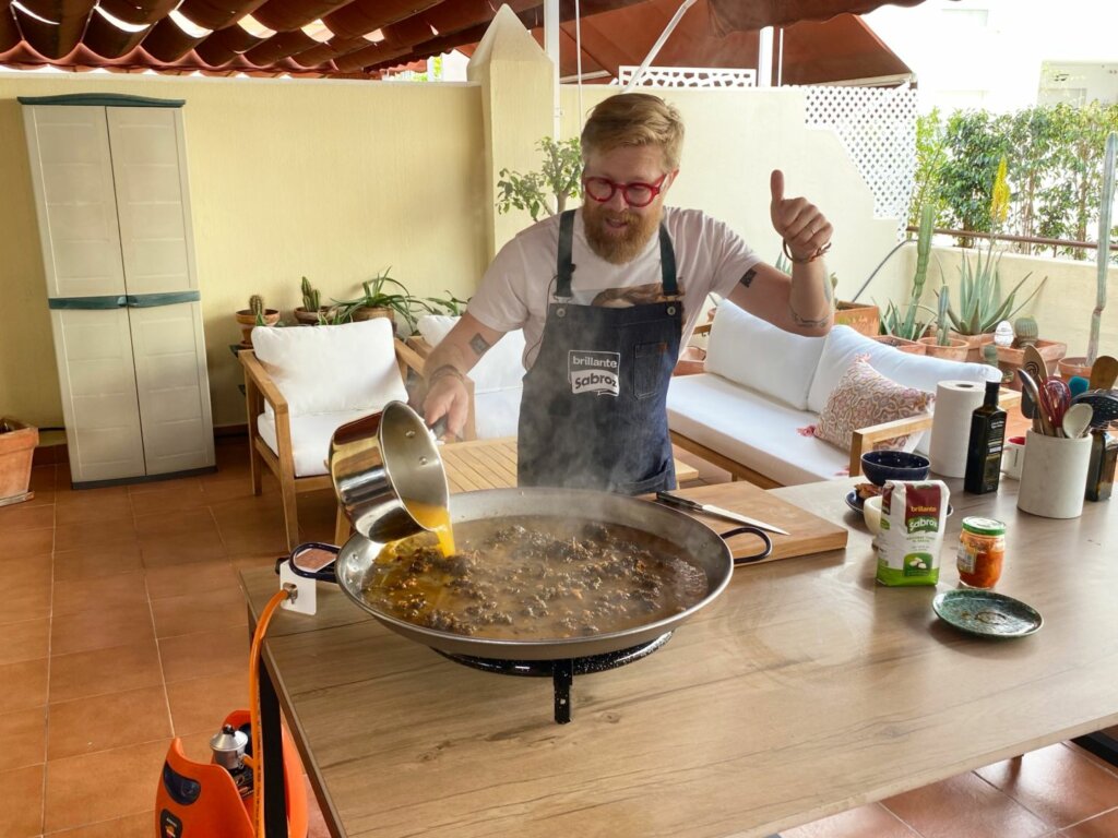 chef agregando caldo de marisco al sartén