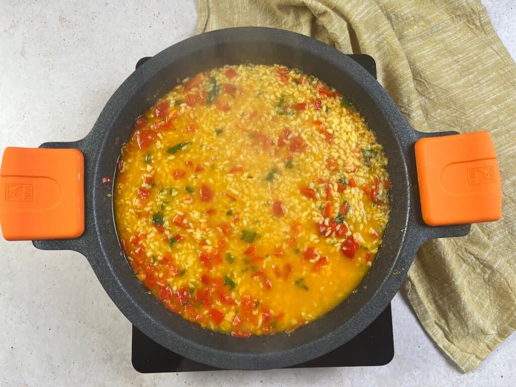 Receta arroz con gambas paso 2 sofreímos el pimiento rojo junto al tomate triturado. Añadimos el arroz e incorporamos el caldo de cocción