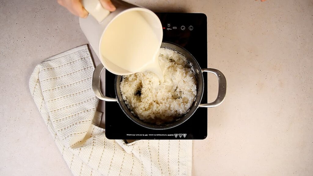 Receta arroz con leche asturiana. Paso 3: Retira las ralladuras de limón y las ramas de canela de la leche e incorpórala al arroz